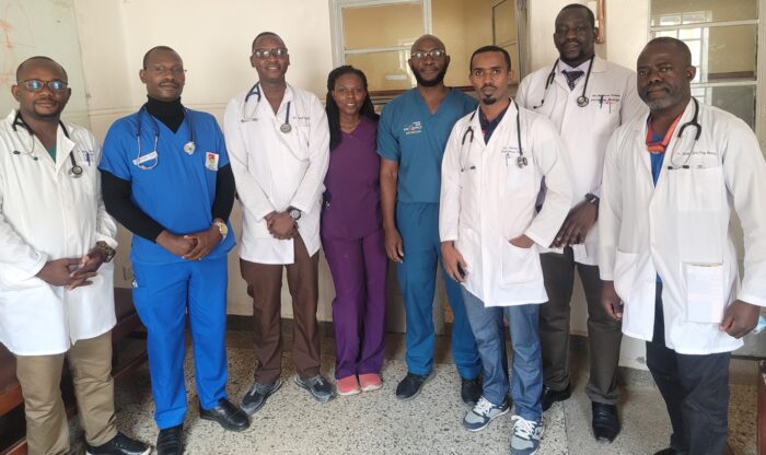 Resident doctors following a morning handover session with Dr. Kenneth Bagonza (center, in blue scrubs), a former Seed educator.